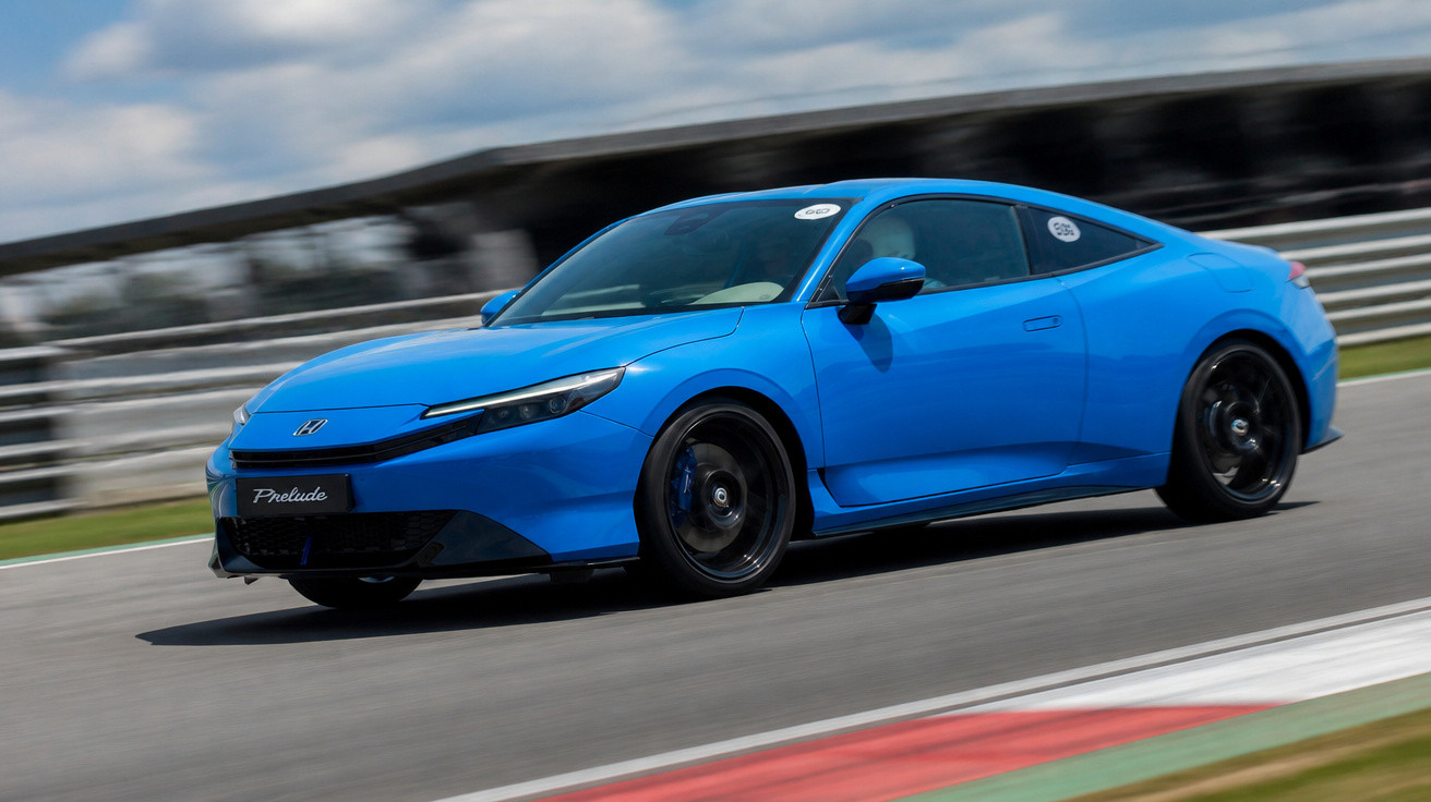 Carro esportivo azul Honda Prelude em velocidade na pista de corrida sob céu nublado.
