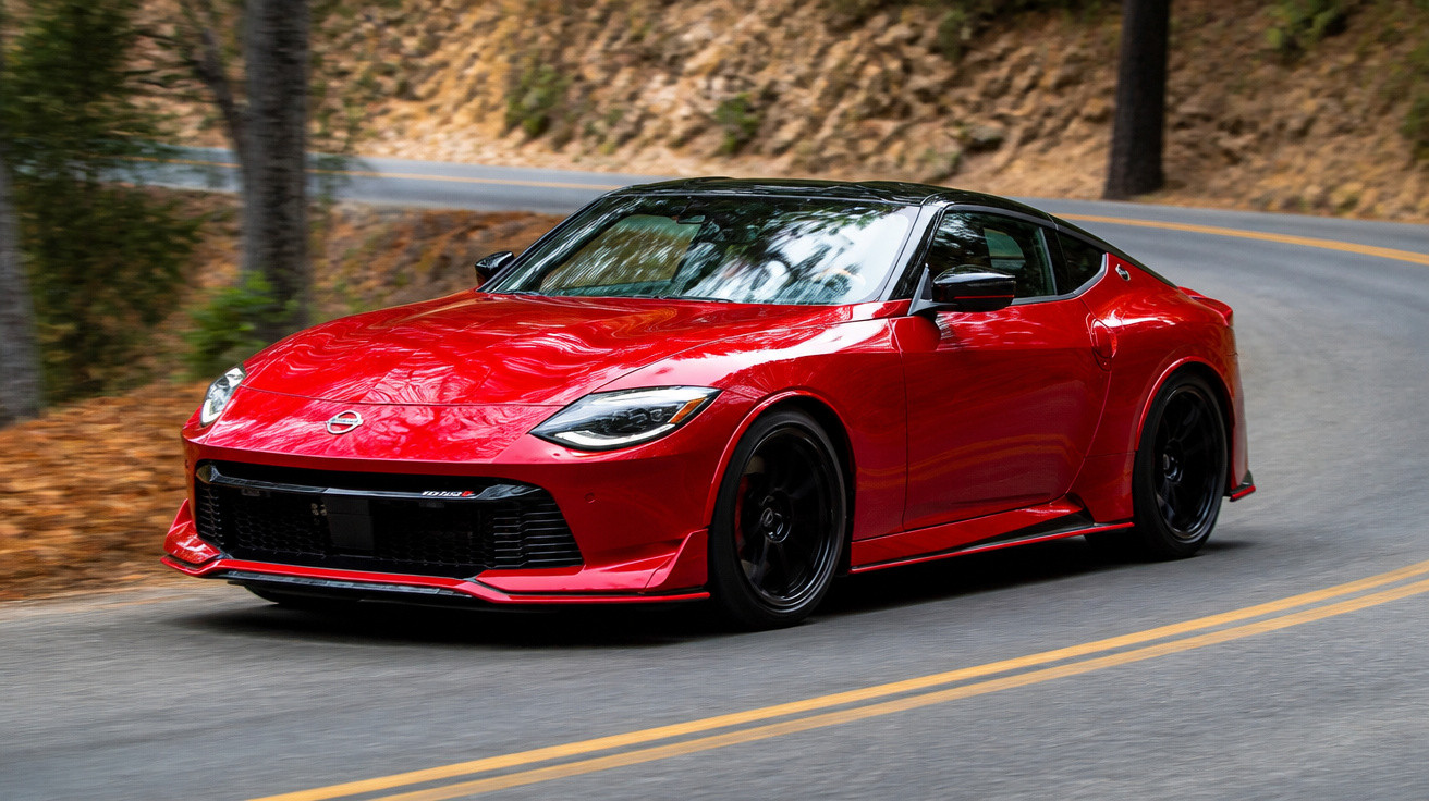 Carro esportivo vermelho em curva de estrada sinuosa cercada por árvores e pedras.