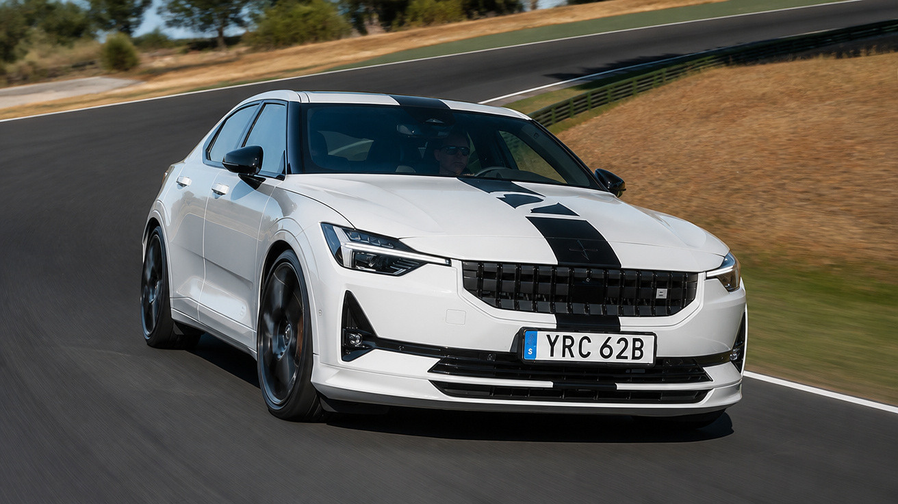 Carro esportivo branco com faixa preta dirigindo em pista asfaltada curva à direita.