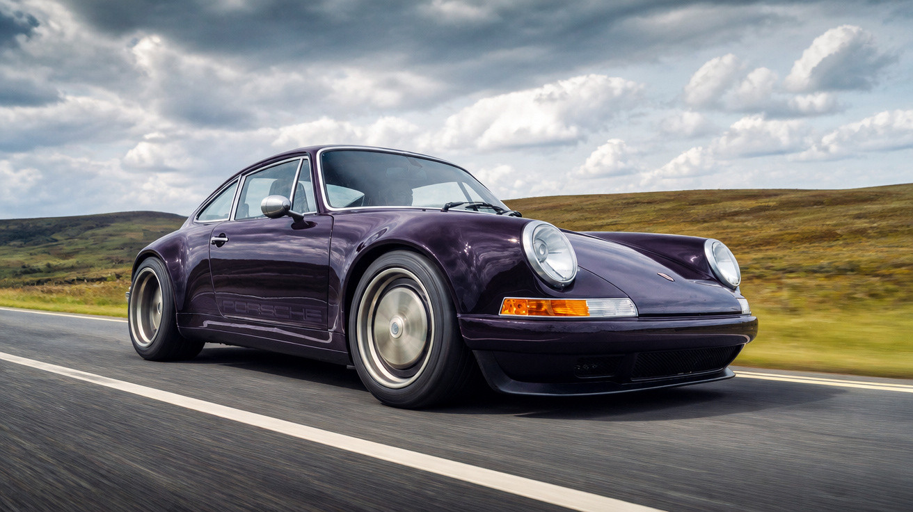 Carro esportivo clássico modelo Porsche 911 na cor roxa em estrada sob céu nublado.