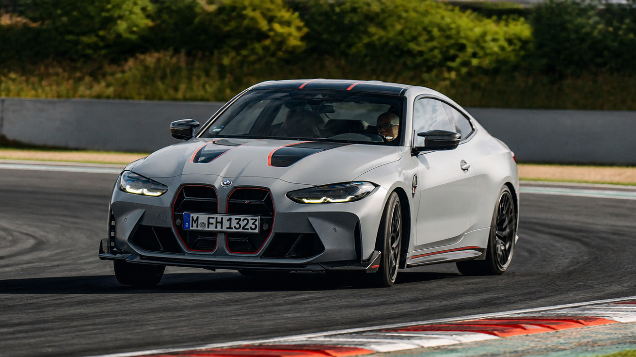 Carro esportivo BMW cinza com detalhes pretos e vermelhos em curva de pista de corrida asfaltada.