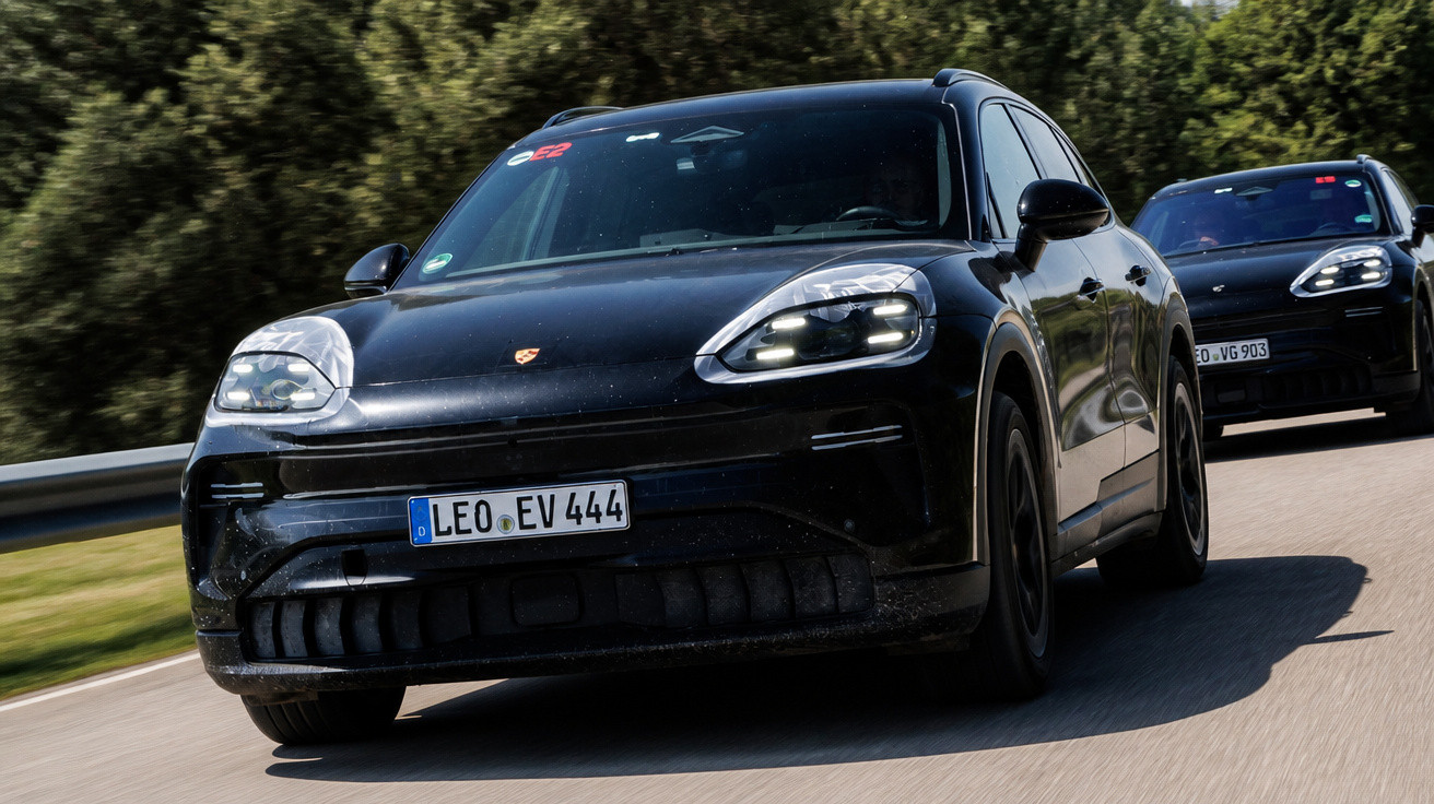 Dois carros pretos em estrada, foco no SUV elétrico Porsche em primeiro plano com placa alemã.