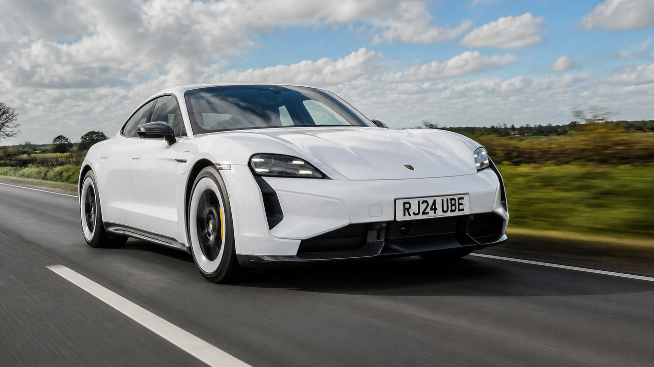 Carro esportivo branco Porsche em alta velocidade numa estrada sob céu parcialmente nublado.