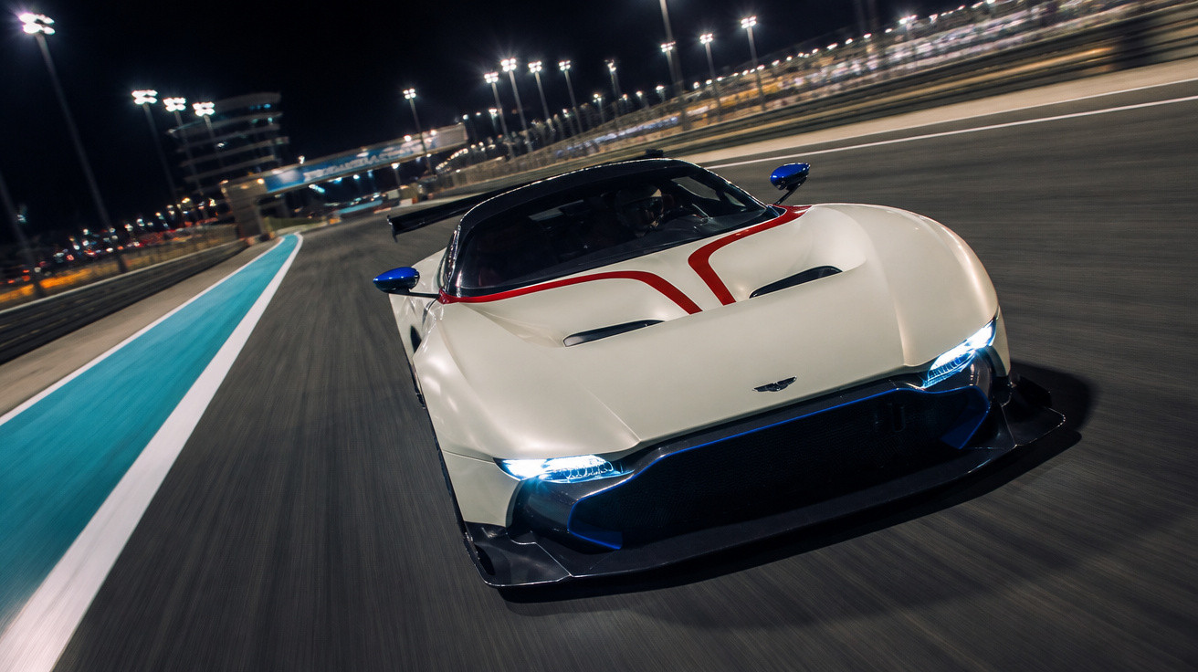 Carro esportivo branco com detalhes vermelhos em alta velocidade em pista iluminada à noite.