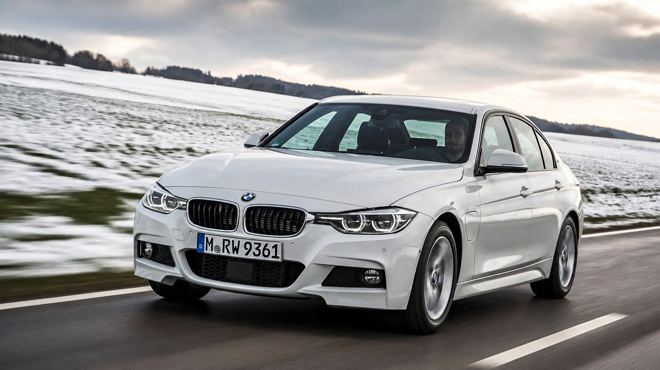 Carro BMW branco em movimento em estrada molhada com paisagem de neve ao fundo.