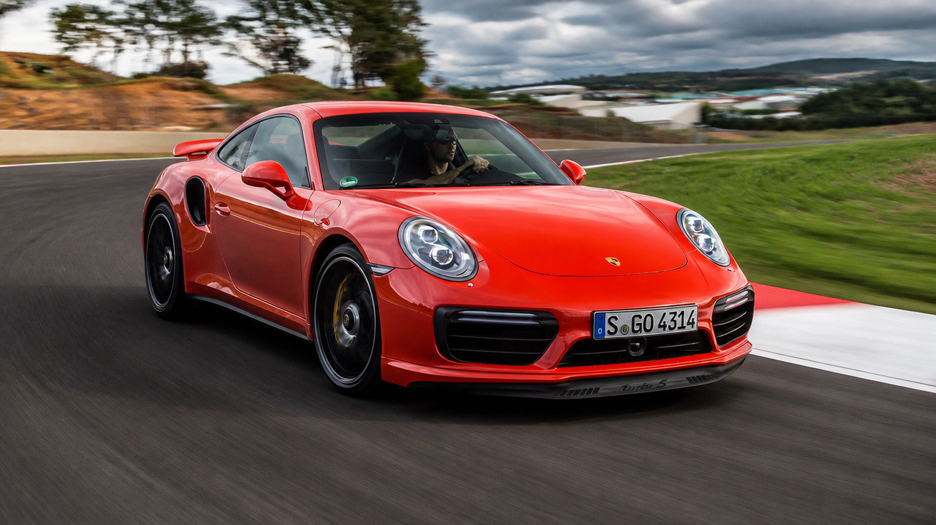 Carro esportivo Porsche vermelho em alta velocidade numa pista de corrida sinuosa com céu nublado.