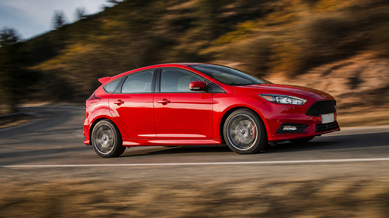 Carro hatchback vermelho em alta velocidade em estrada com fundo desfocado e paisagem natural.