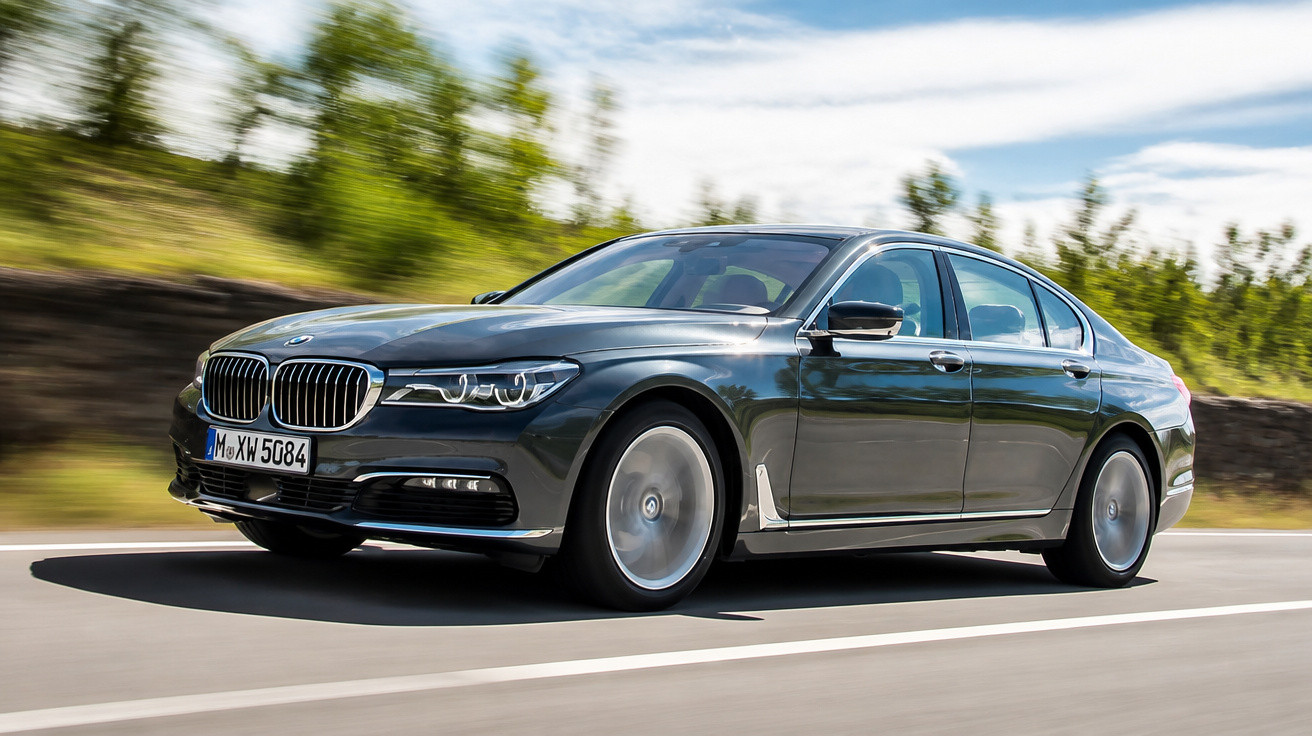 Carro BMW preto modelo sedan em movimento numa estrada com árvores ao fundo.