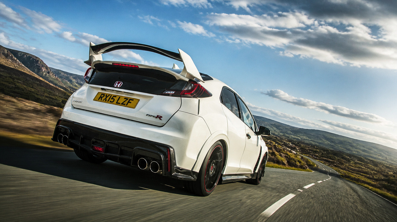 Carro esportivo branco Honda Civic Type R em estrada sinuosa com céu parcialmente nublado ao fundo.