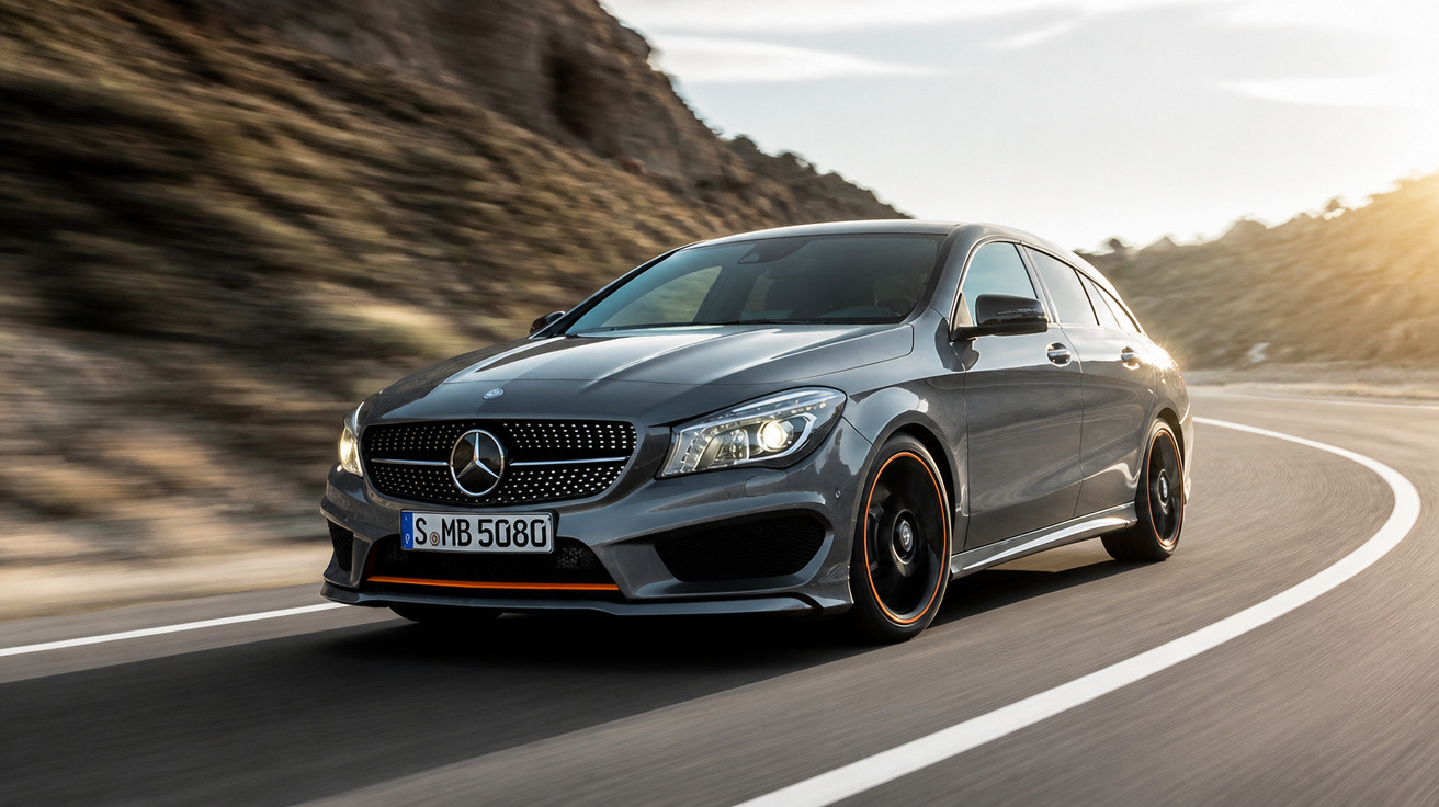 Carro Mercedes-Benz cinza em estrada sinuosa com paisagem montanhosa ao fundo ao pôr do sol.